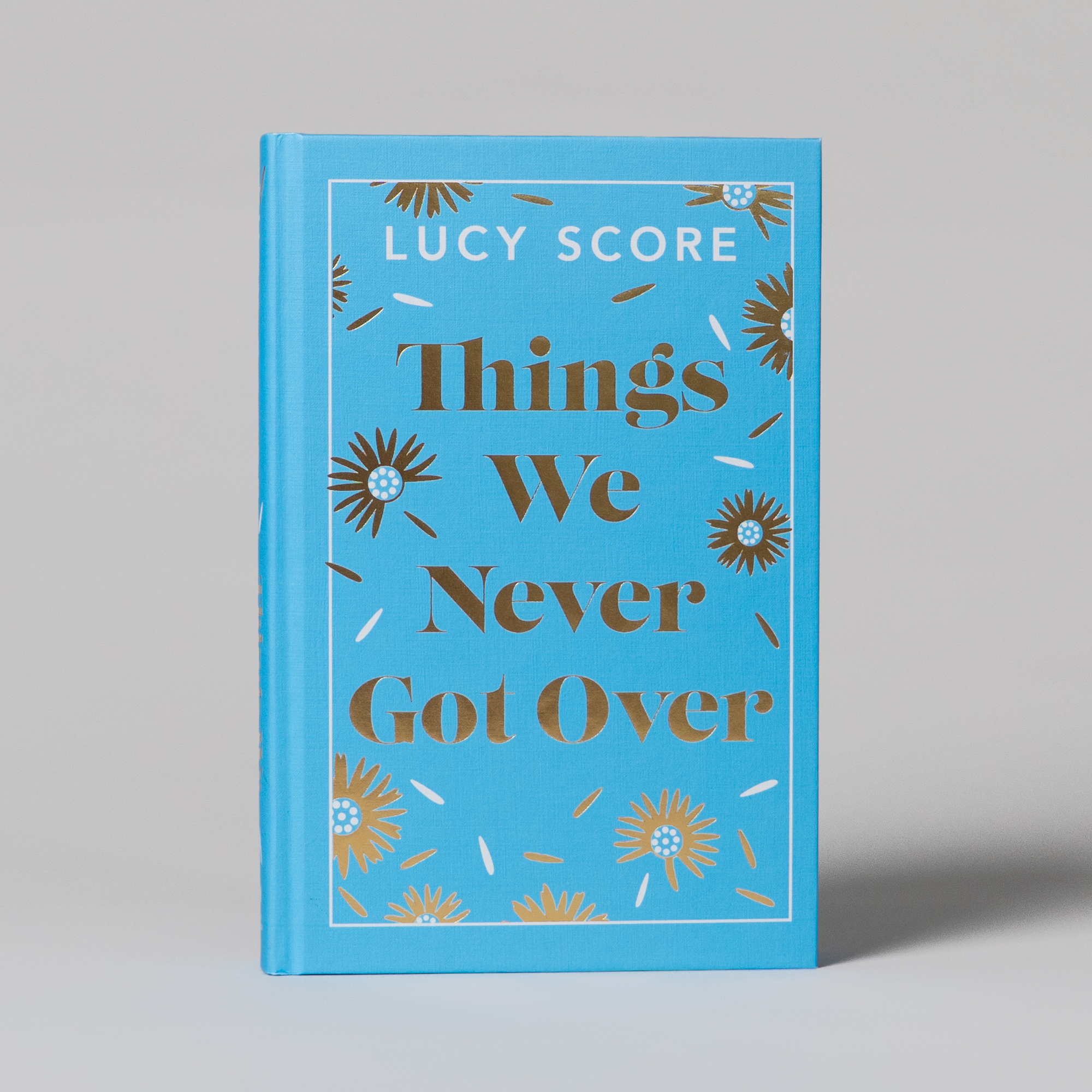 Things we Never Got Over by Lucy Score. Featuring a light blue clothbound cover with flower illustrations and a blue sprayed edge.